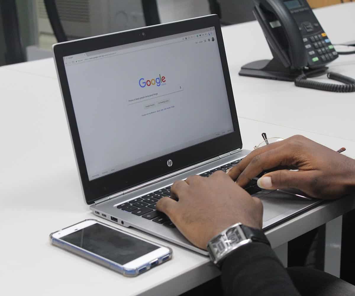 Man Typing on Google.com on a Laptop